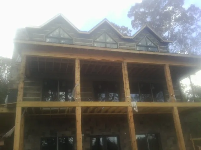 Dormers and porch framing on a large log home under construction — Roof Coating work by our crew in Yorktown